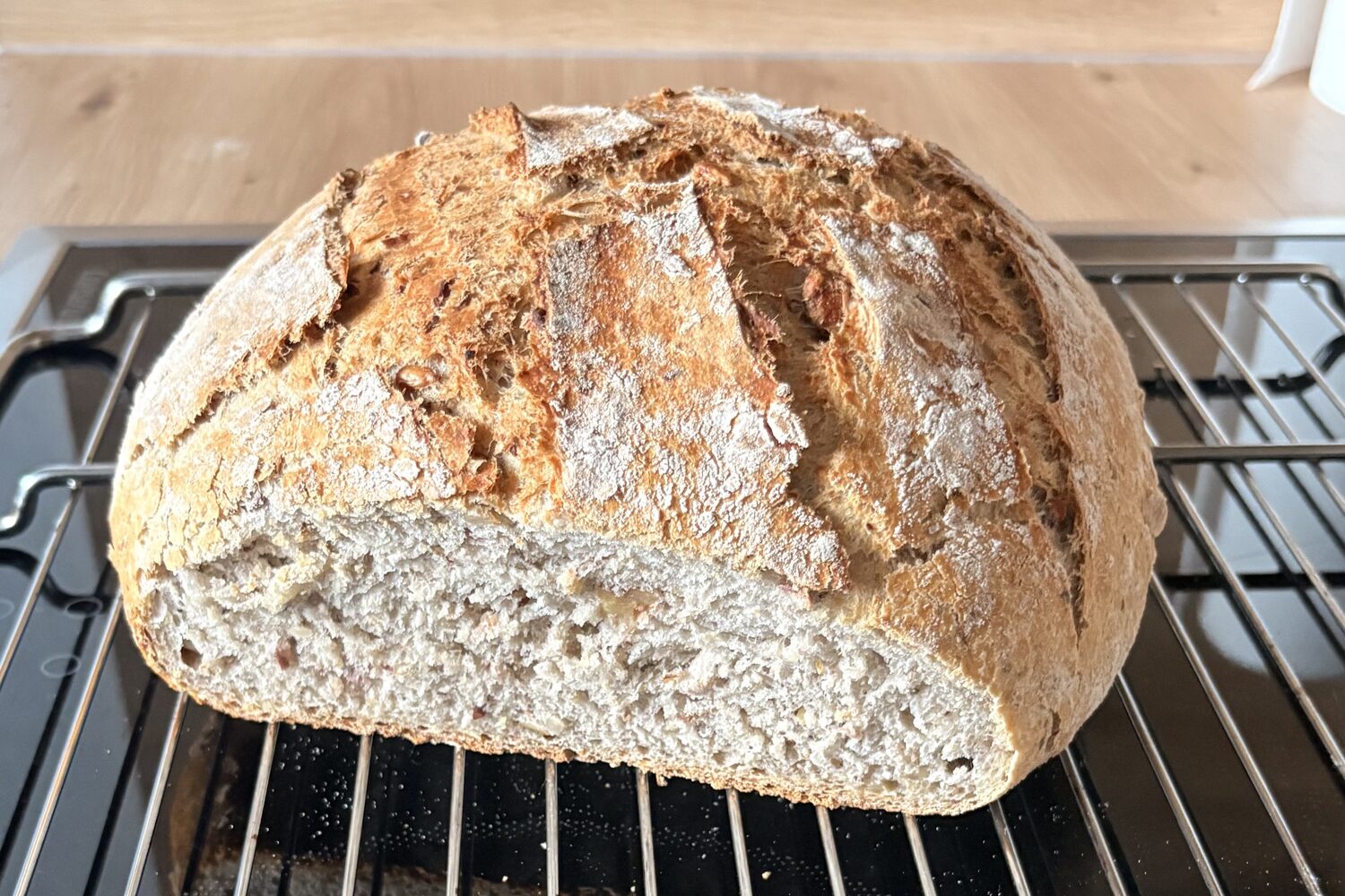 Frisch gebackenes Dinkelbrot mit Kruste und Kernen auf dem Ofenrost